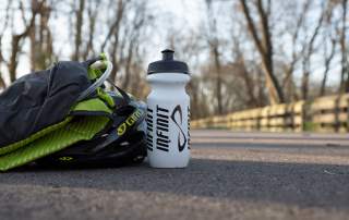 water bottle on bike path with hydration pack and helmet
